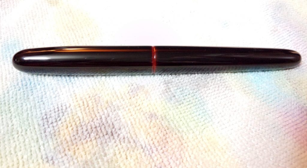 The capped pen. You can see the red layers where the cap meets the barrel.